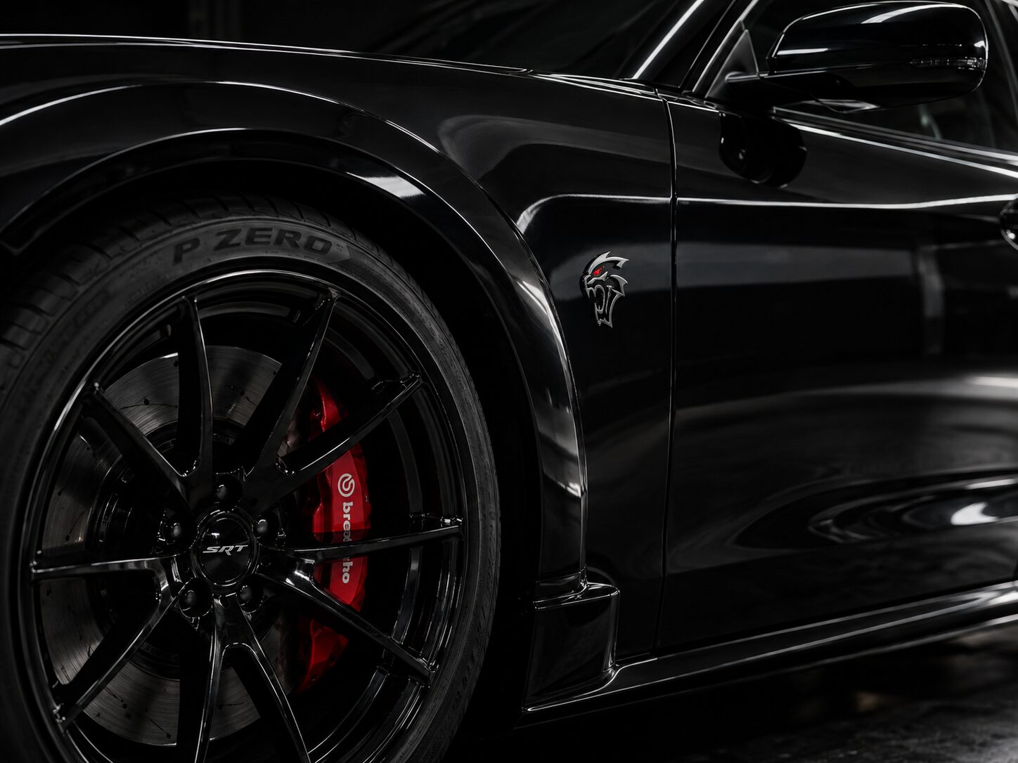 Black car fender and wheel with red brake calipers